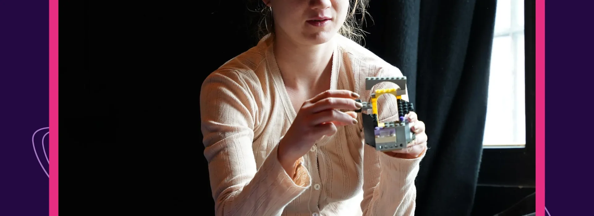 Auf dem Bild ist Sophia Eisenhut zu sehen, wie sie ein Legobauwerk in der Hand hält. Oben links steht Litnova. Unten rechts steht Prosanova.